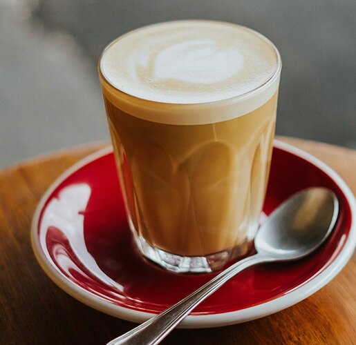a table with a cortado coffee and a sugar pot